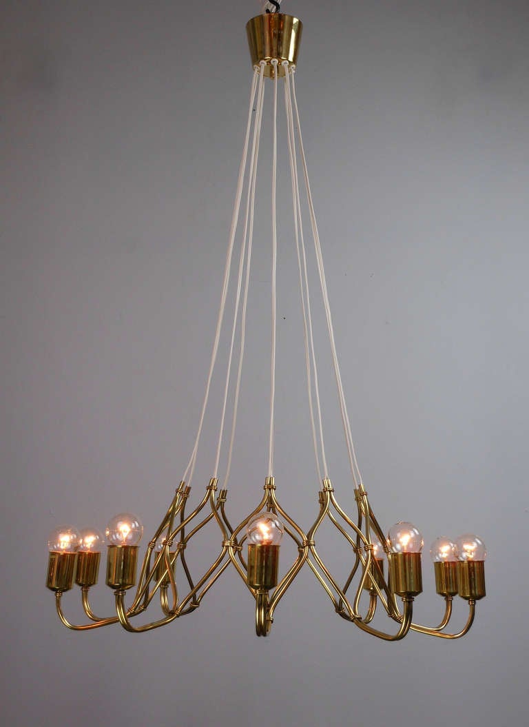 The canopy issuing cords supporting the intertwined brass lozenge frame fitted with 10 light holders.