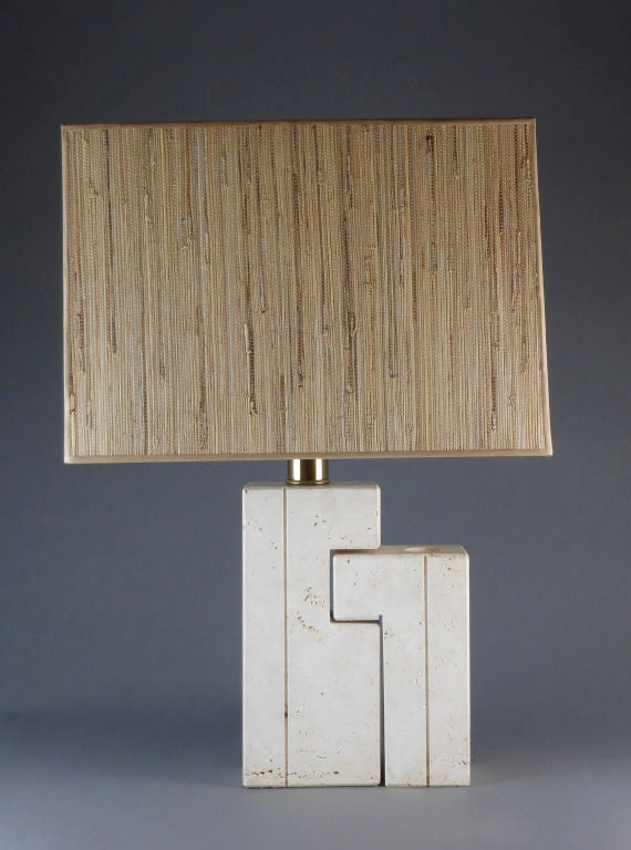 The interlocking geometric forms with incised lines, the larger column supporting the lamp, the smaller column containing a circular vase opening.