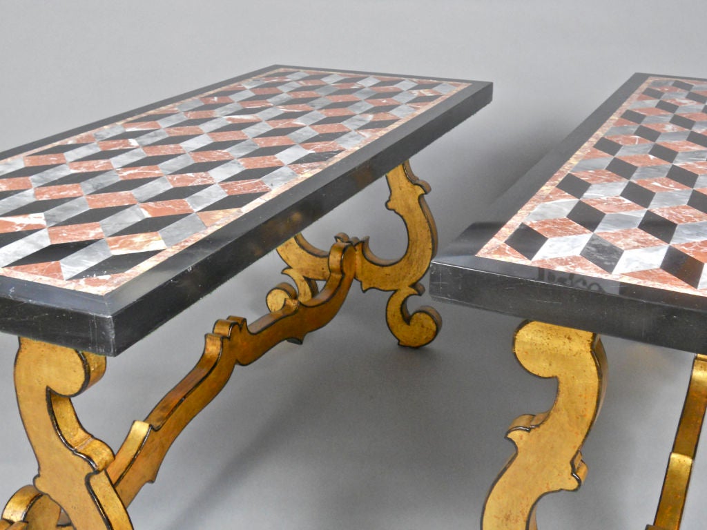 The specimen marble tops have a black paragone and Spanish brocatalle border surrounding the trompe l'oeuil paragone, bardiglio and rosso marble reserve. The bases of black bordered gilt C and S scroll legs are joined by a conforming stretcher.