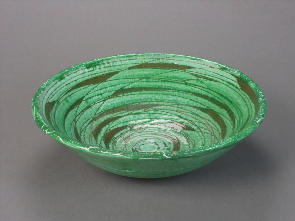 The 1950s era bowl is decorated with an abstract glaze of dynamic circling lines. Signed MG.