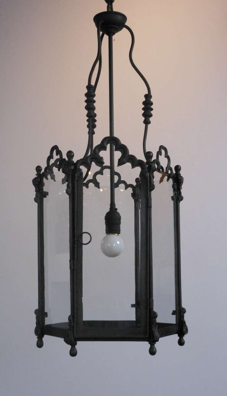 The hexagonal hanging light with six scrolling arches, surmounted with three serpentine supports.