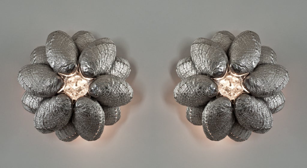 Each wall light has a circular backplate fitted with two circles of overlapping shells centred by a glass star form.