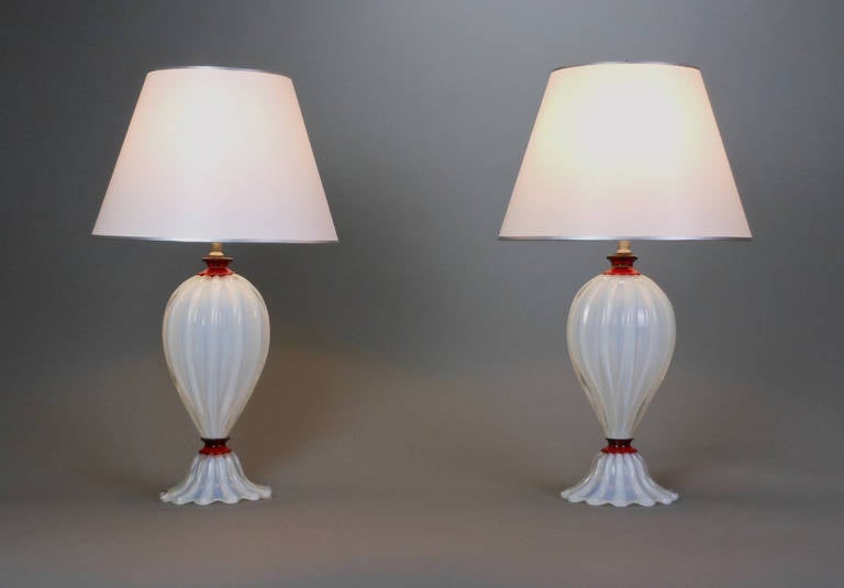 Each Italian opaline lamp is of fluted baluster form on a domed scalloped edge base. In the manner of Barovier.

Measures: Height to base of light socket: 14"
Height to top of finial: 25"