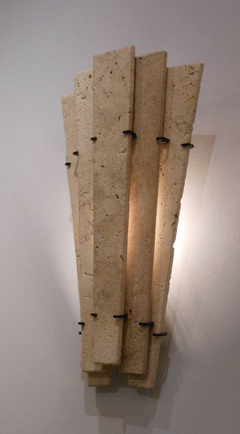 The tapering wall lights are each composed of overlapping, vertical travertine panels fitted to metal backplate.