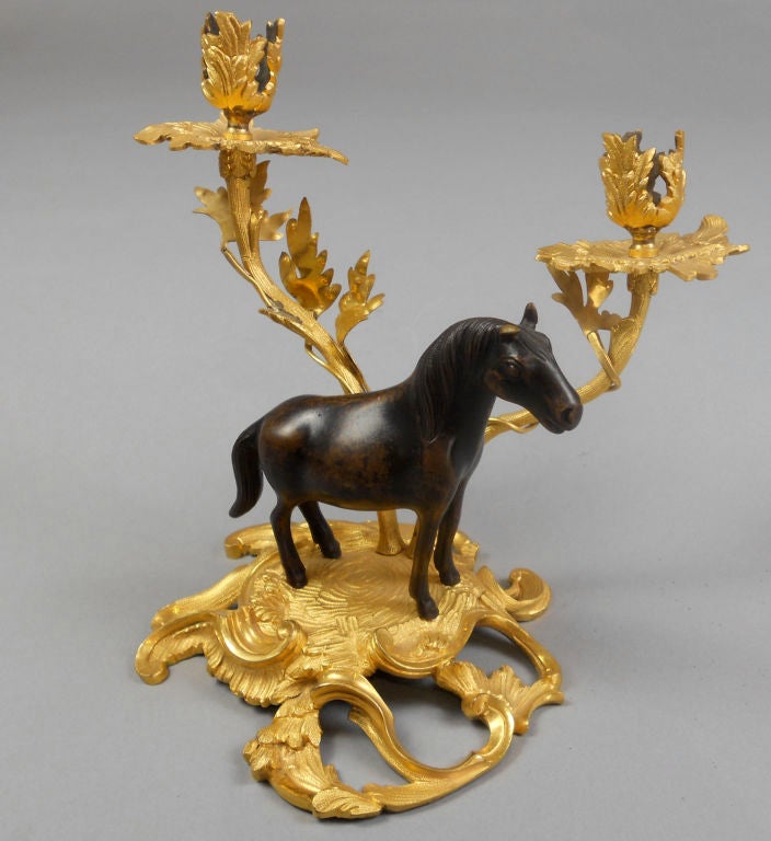 The Chinese patinated bronze horses have French Rococo gilt bronze mounts.
In mirror image of one another, the horses stand on a foliate C-scroll base fitted with two candle branches ending in foliate bobeches.