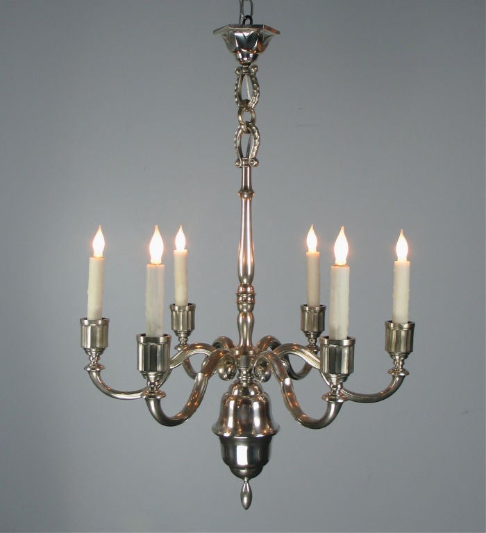 The octagonal canopy connected by hammered scroll links to the slender baluster standard issuing six scroll trumpet arms with faceted candleholders, above an urn ending with an oval finial. Stamped on the canopy HB KA8. By Herman Bergman.