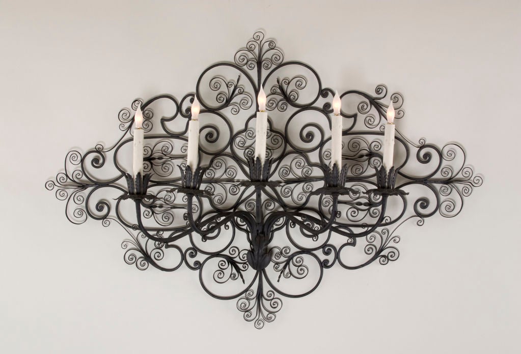 Each wall light has an open scroll work back issuing five S-shape candlearms with foliate candleholders.