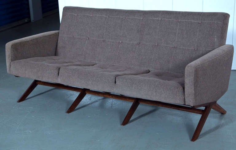 A highly structured Mid-Century three person sofa, with button tufted upholstery.