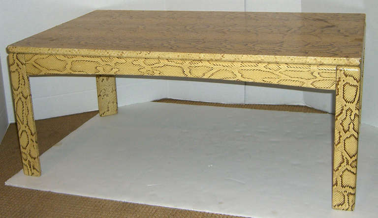 A yellow Python snake skin covered wood Parsons style cocktail table. Triangular legs, and a floating top add interest to the typical Parsons look.