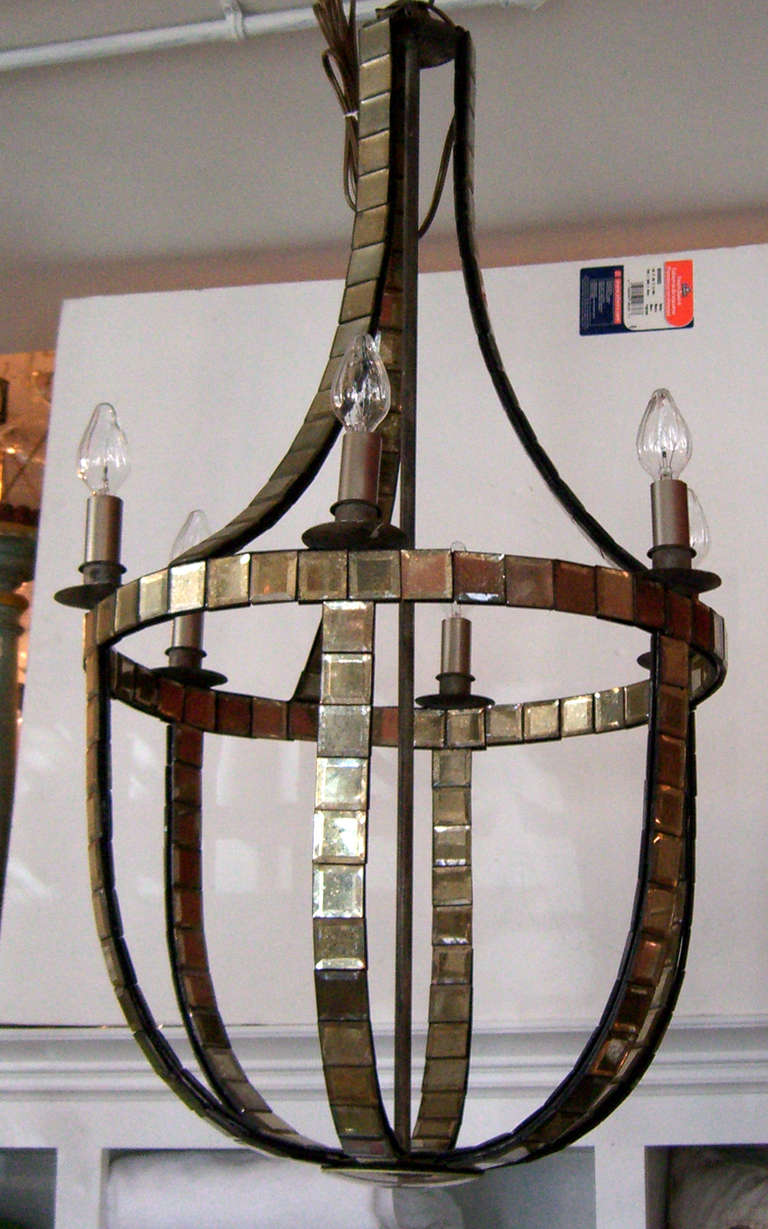 An open design six candelabra light chandelier comprised of antiqued mirrored tiles that mimic the mirrored designs of French designer Serge Roche.