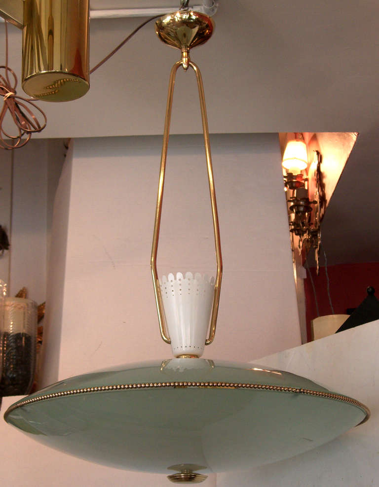 A frosted glass saucer form shade hangs from a fixed double arm. A beaded brass rim adorns the glass, and a punched white enameled metal cone tops the shade.