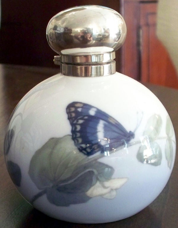 Royal Copenhagen porcelain bottle handpainted by painter #70 with sweet pea flower and landed butterfly.  The neck and hinged lid are George Betjemann & Sons, English sterling silver.