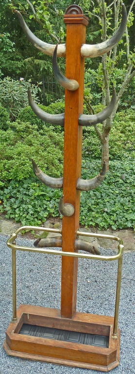This 19th century antique coat stand has cattle horns as hooks the column is solid antique oak, and the rail is brass.