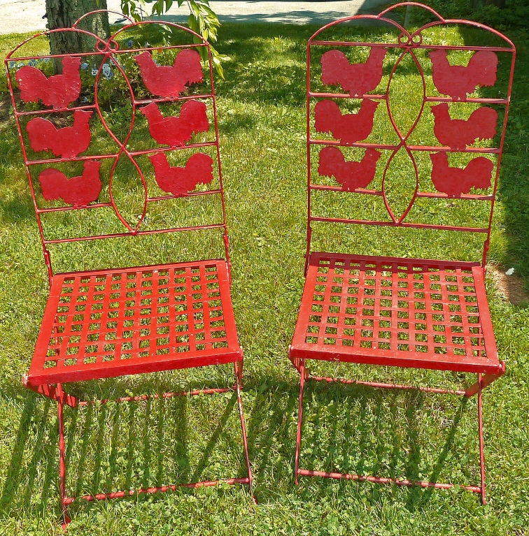 These vintage wrought iron folding garden chairs are painted in a bright red, and feature hand cut metal roosters on the backs.  They fold up easily for storage.
