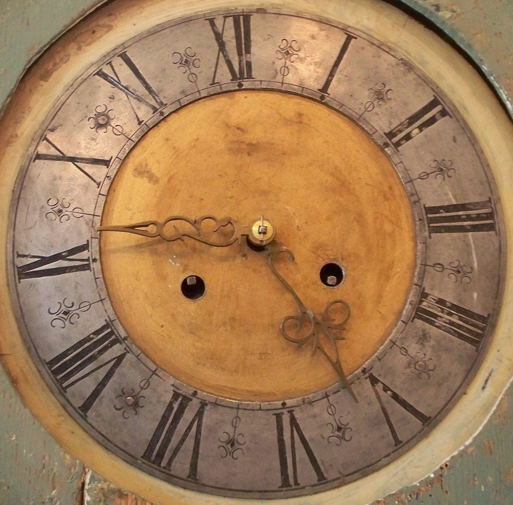 a Swedish long-case clock with with original paint. The face is engraved metal with ornate brass hands. The clock has an eight-day movement and strikes the hours on bells mounted above the clock mechanism. The weights were made of cast iron.