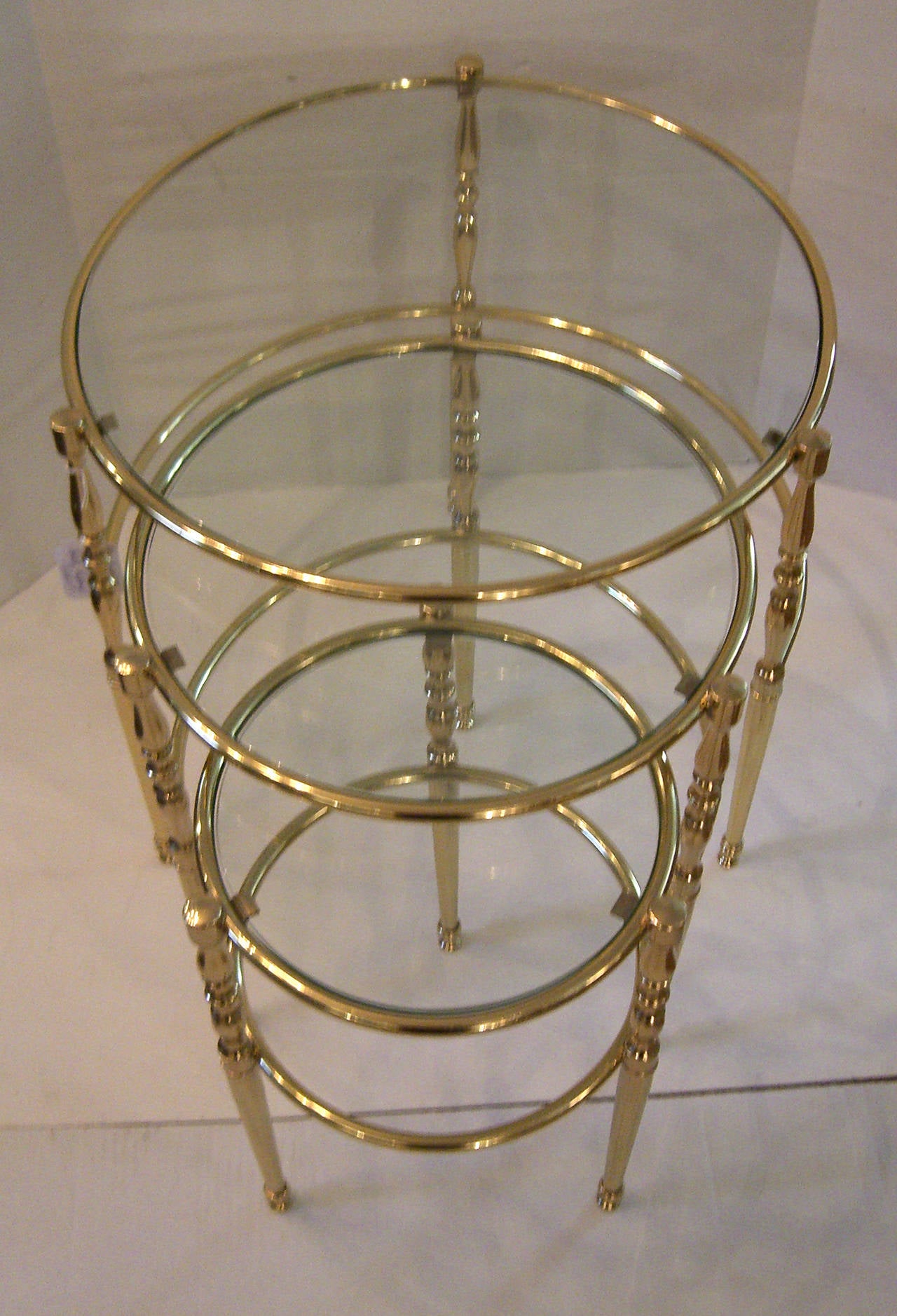 A set of 3 rare circular brass nesting tables with clear glass tops. The brass has been polished and lacquered.