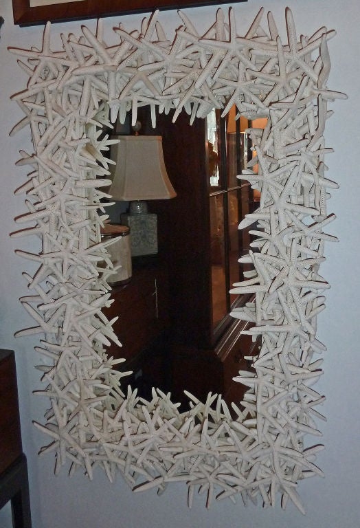 The rectangular frame of this eye-catching mirror is created by layering natural bleached starfish. It is designed and made by artist Maralyn Menghini.