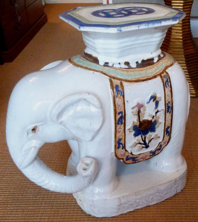 A ceramic garden seat or side table in the form of an elephant.  Glazed in white with accents of bright color.