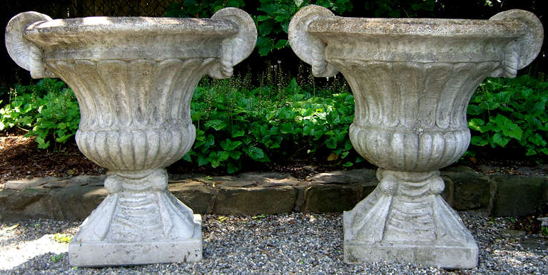 A pair of large cast stone garden urns featuring classic decorative elements. The bases have draping detail, while the handles feature a rope detail.