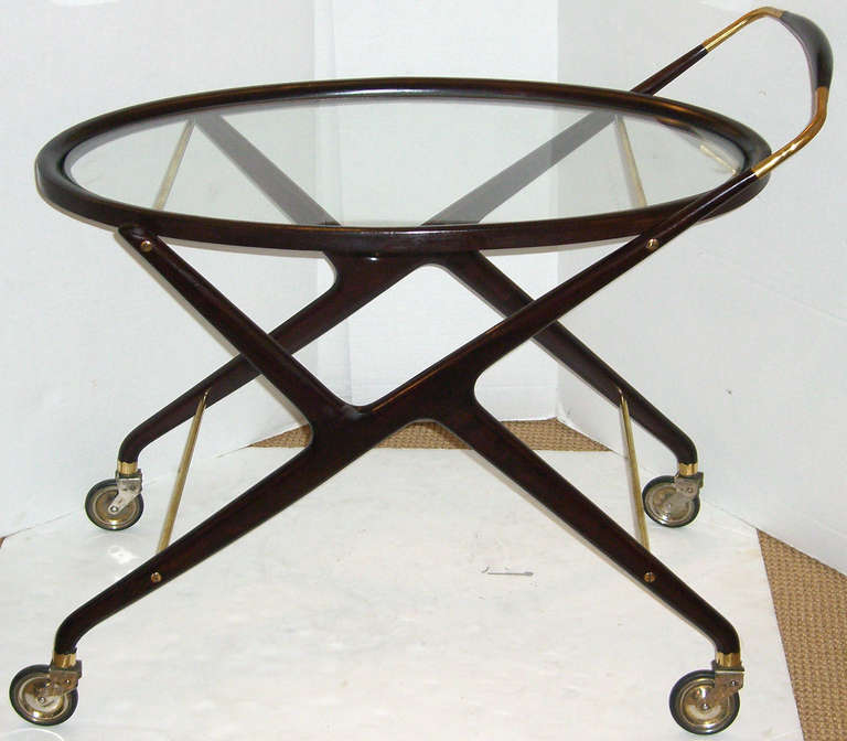 A Mid-Century Modern solid walnut rolling cart with brass handle and stretchers.