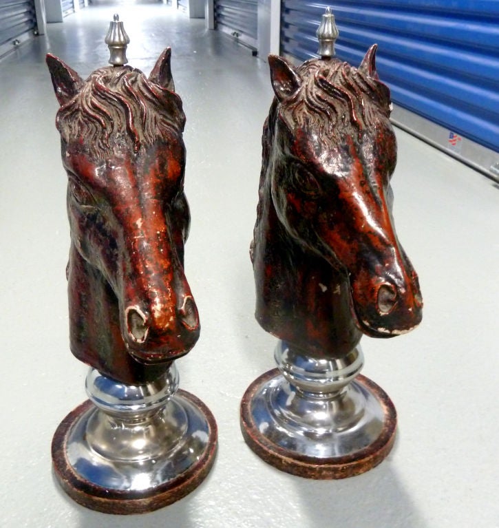 Deeply detailed terra cotta horse heads on chrome bases. Glazed in variations of red browns and topped with finials.