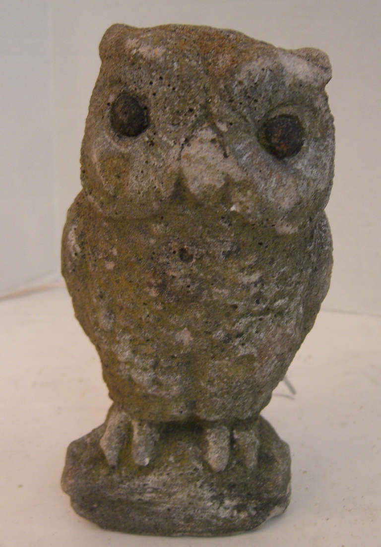 A small cast stone owl perched on a rock with painted eyes.
