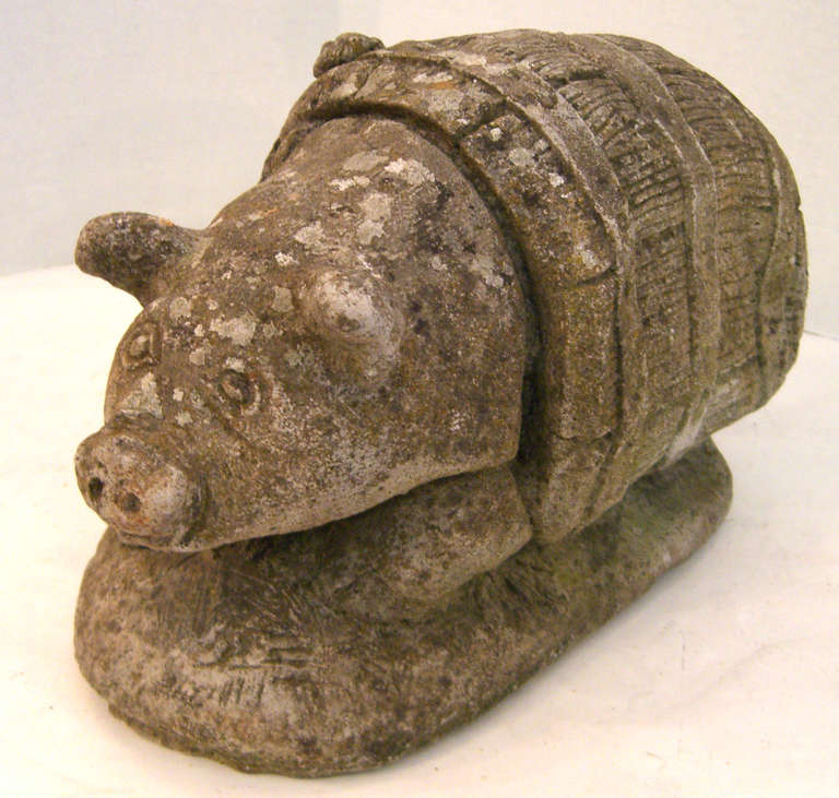 A vintage English cast stone pig in a barrel on an oval base.