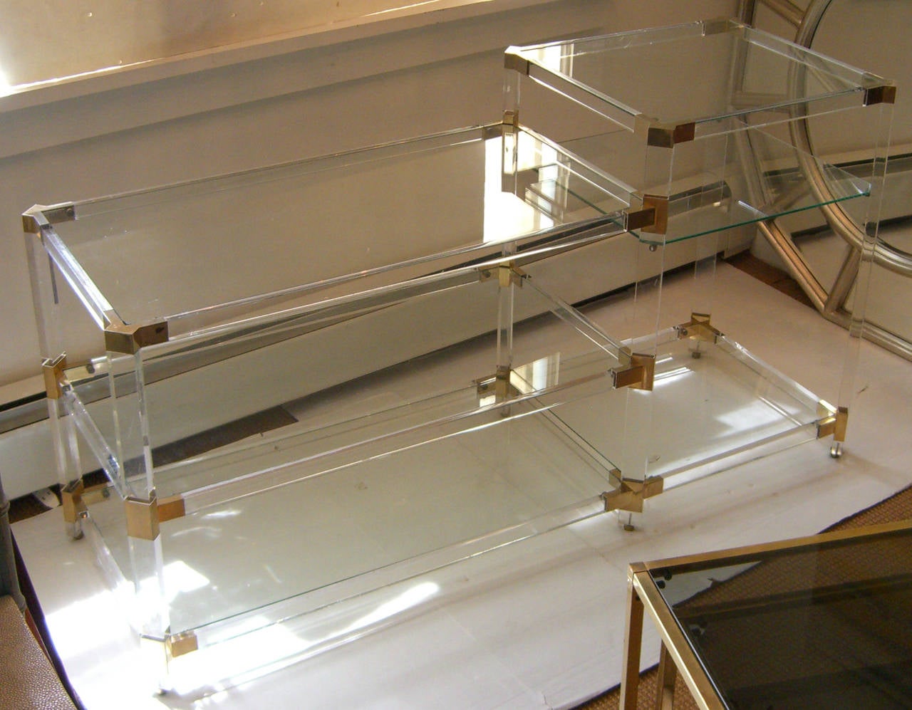 A very useful, yet unobtrusive console shelving unit. The frame is Lucite with brass plated corners, and the six shelves are glass. The entire piece rolls on brass rolling ball bearings.