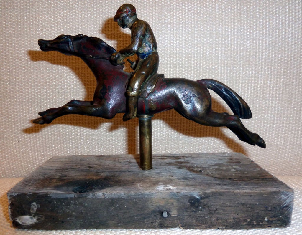 mounted on wood the horse gallops as the jockey wearing a sash of blue holds his crop