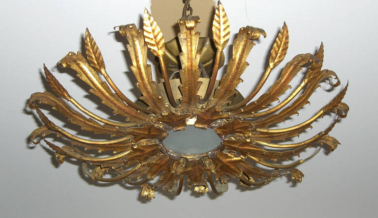A very interesting French 1940s style ceiling light made up of alternating leaf design hand-cut metal arms. A frosted glass shade covers a single candelabra bulb socket.