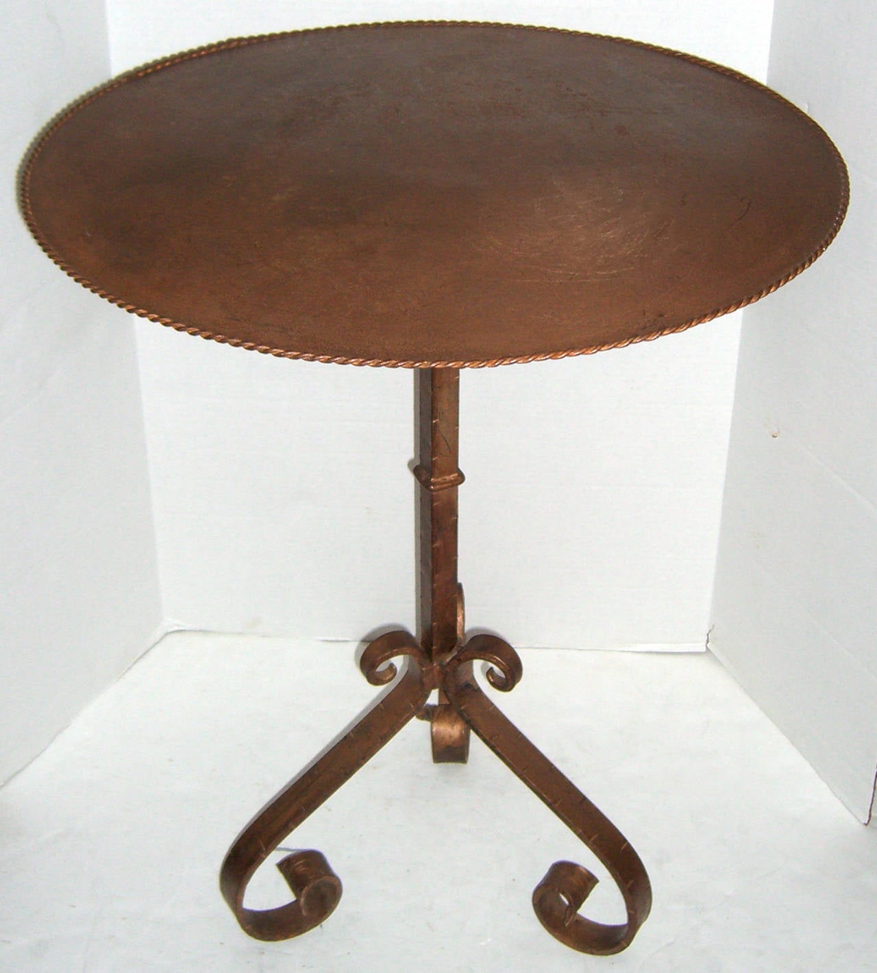 A tripod gilt iron candle stand base is re-purposed as a bistro table with the addition of a patinated metal top.