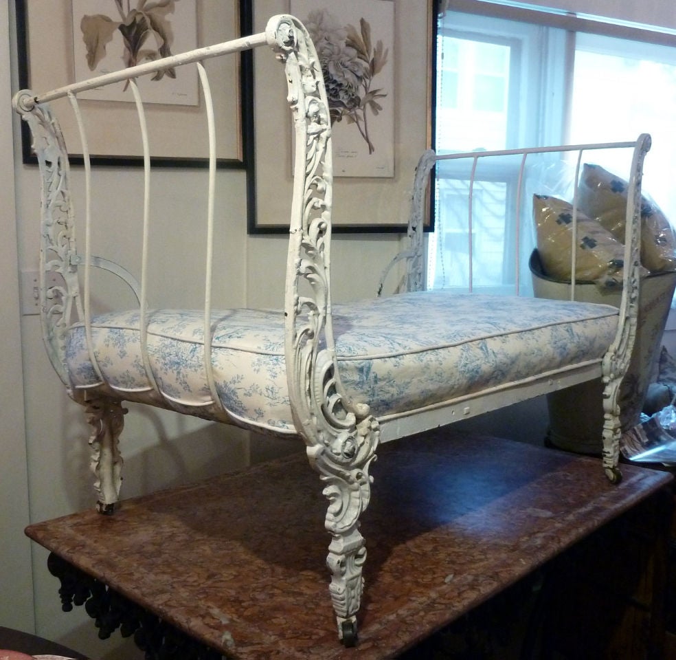 this special antique French daybed has detailed scroll work emanating up from the feet that are set on casters.