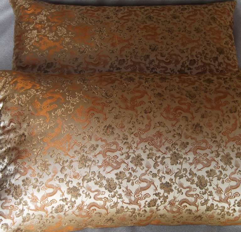 Pair of pillows with a beautiful floral and dragon print. Silk material is perfect for an added elegant touch.Colors of gold, orange, and light olive-brown.