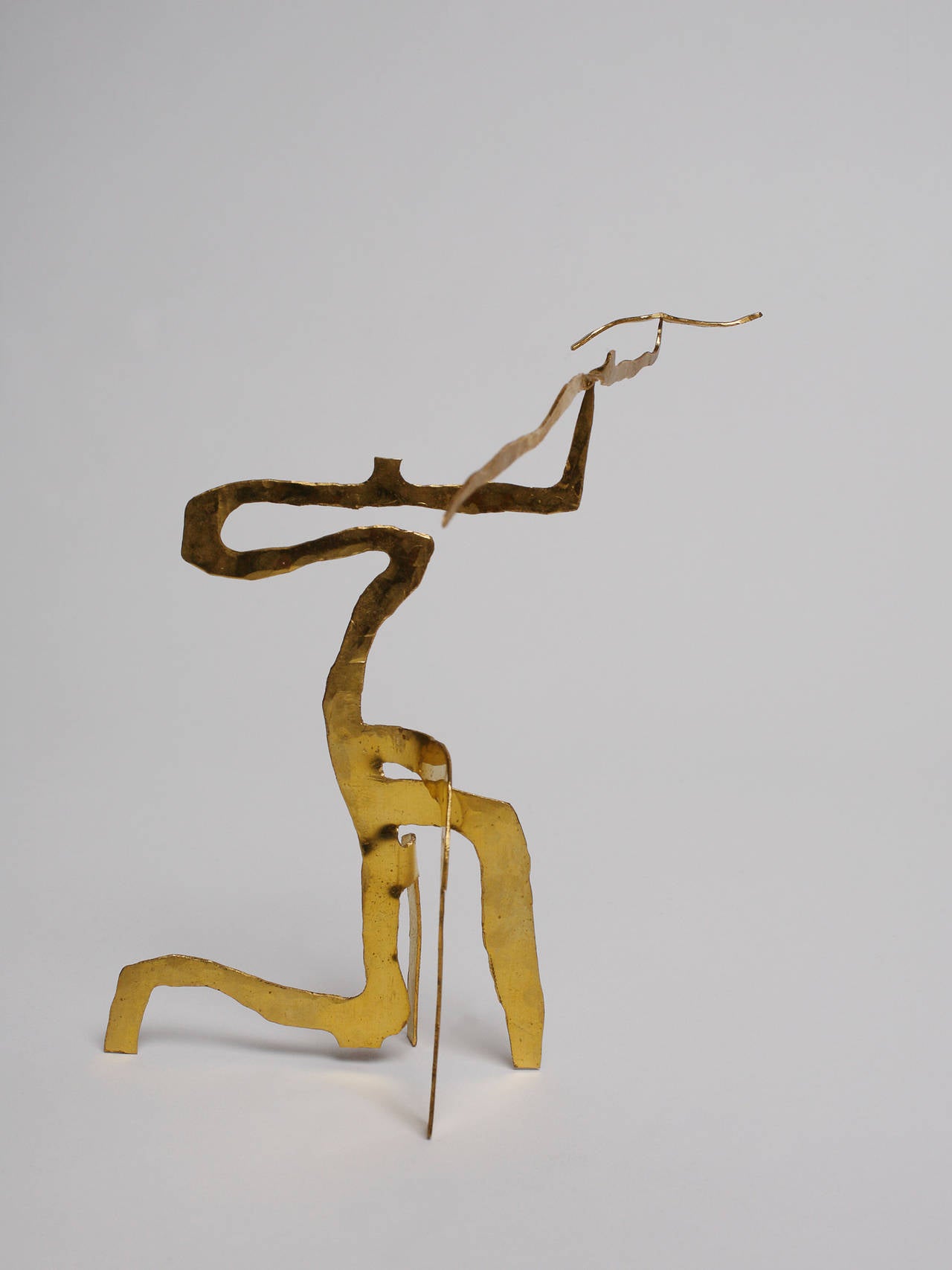 A handcrafted stabile sculpture composed of 3 pieces balancing one on the other from a needle point. This piece is a miniature of a monumental stabile in wood created by the artist in 2011

The artist uses brass that he hand-hammers to give it