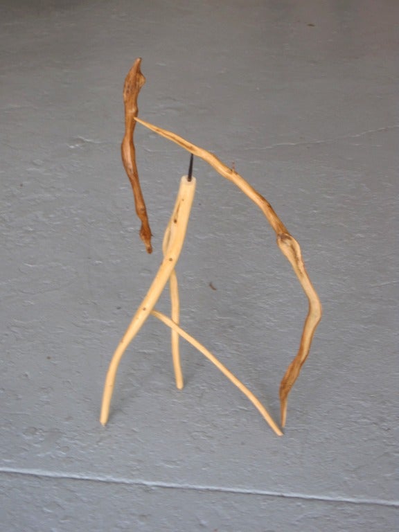 A  sculpture by Jacques Jarrige made of 4 pieces of found sculpted wood. The center base holds a small piece on which stands  2 movable branches.
