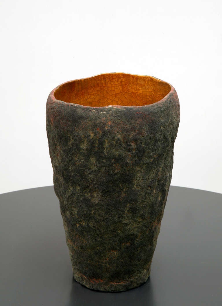 A tall vessel with 22 k inside made by artist Cristina Salusti
Beginning with a ball of clay, she pinches it into vessels and textures them with stone fragments. After multiple firing it was finally lustered with 22K gold . Its volcanic-like outer