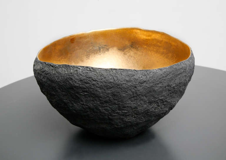 A medium round vessel with 22 k inside made by artist Cristina Salusti
Beginning with a ball of clay, she pinches it into vessels and textures them with stone fragments. After multiple firing it was finally lustered with 22K gold . Its volcanic-like