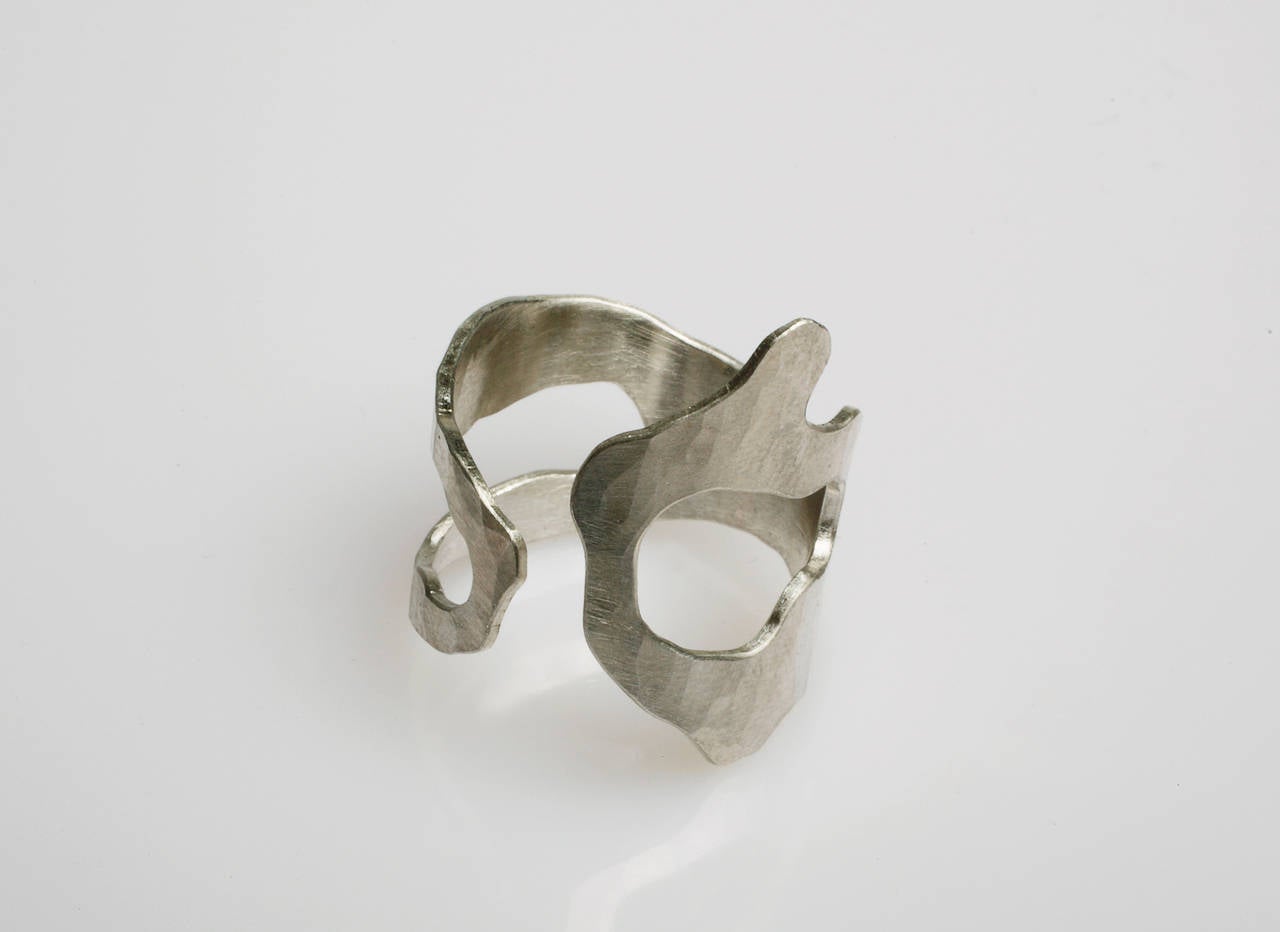 An amazing piece of jewelry hand-sculpted and hammered in sterling silver.

This wearable art piece has three variations, two with three negative spaces and one with three. The ring fits comfortably on the finger for everyday wear.

Also