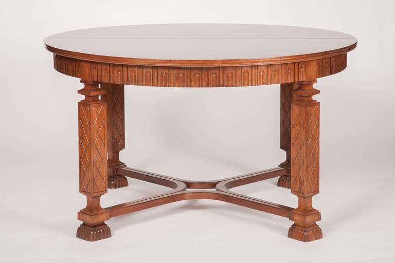 This fine Swedish Grace period walnut dining table has a circular top with highly figured matched flame veneers, above a carved gadrooned apron, supported by four carved square legs, joined by a stretcher, raised on stylized lion paw feet, all in a