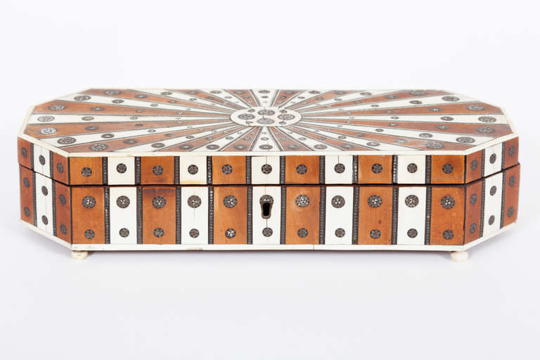 This fine Indian sandalwood box is of elongated octagonal form with Sadeli work inlay of pewter, ivory and ebony.