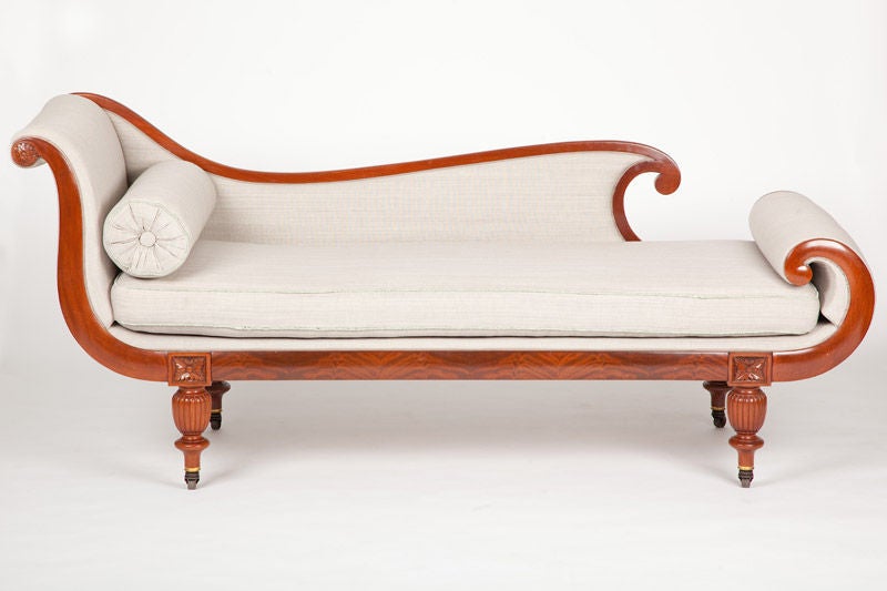 This American Classical period day bed, or recamier, was made in Boston from  richly colored, figured mahogany, with a strongly curved foot rail, the back at one end terminates in a carved rosette, the lobed and turned legs terminate at the figural