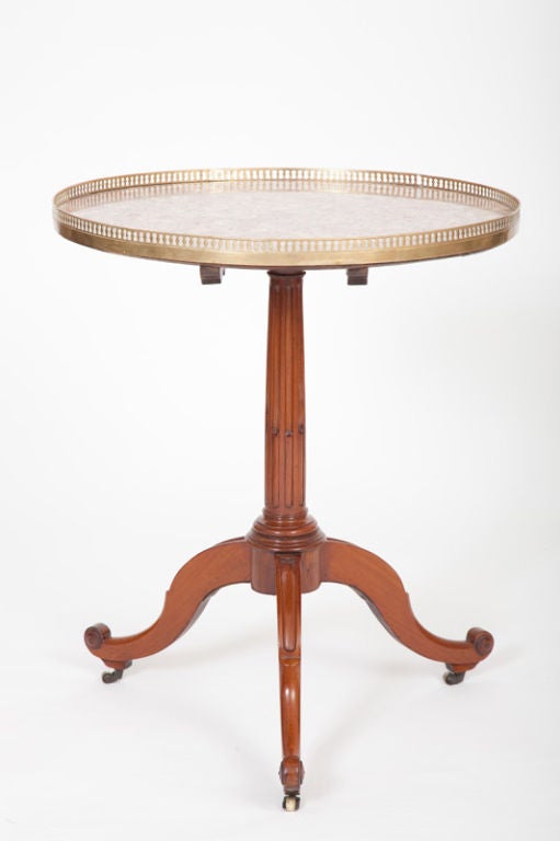This French late Louis XVI period mahogany guéridon has a circular breche violet marble top with a pierced bronze gallery and a tilting standard, with original fittings, on a stop-fluted columnar support, raised on curving tripod legs ending in
