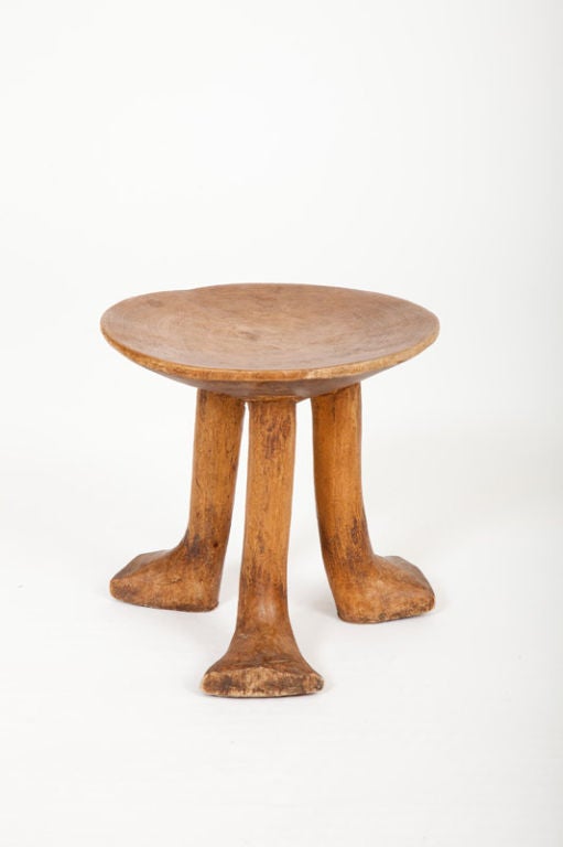 This small African tripod stool was made by the Pokot Tribe from Kenya. It was carved from one piece of wood with anthropomorphic legs.