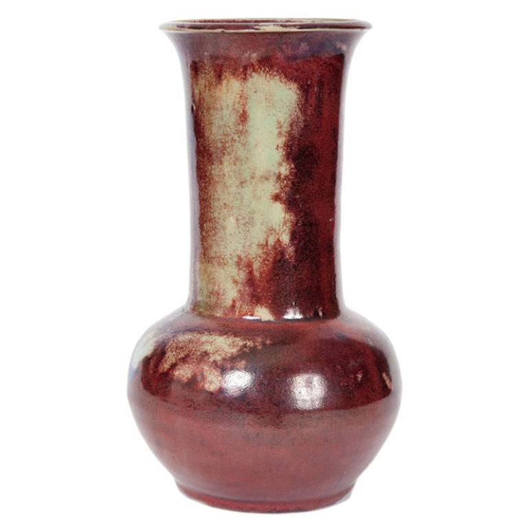 This French Art Nouveau vase has a long wide neck and a bulbous base, all decorated with reddish flambe glaze with light green tones.