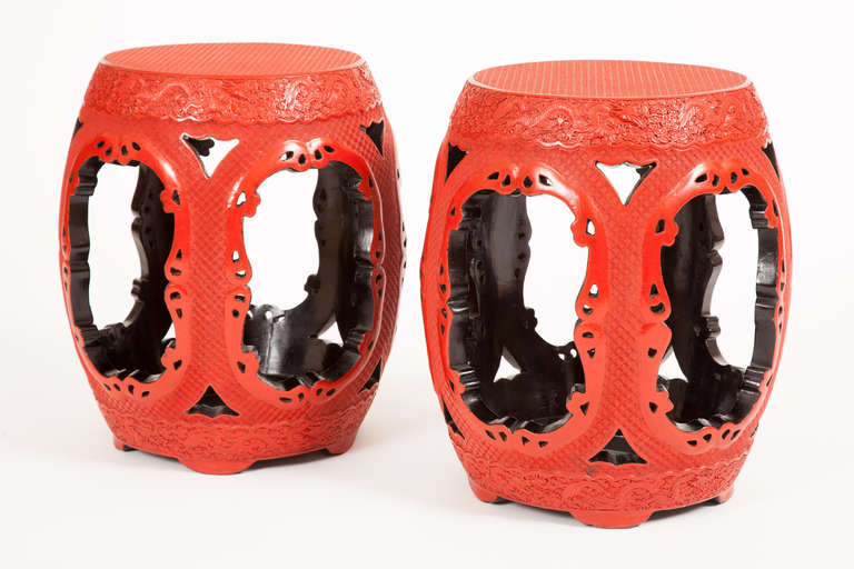 This fine pair of nineteenth century Chinese Qing Dynasty cinnabar stools each has intricately carved and modeled decorations of dragons in clouds around the top rim and tiny squares on the top and sides on all a red lacquer ground, with shaped open