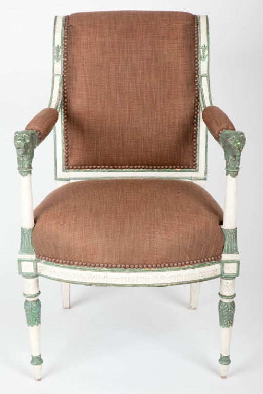 This rare Italian armchair, or poltrona, has finely detailed neoclassical motifs, including lion head form hand rests. In contrast to the crisp white paint, elements have been painted dark green in imitation of patinated bronze, following a fashion
