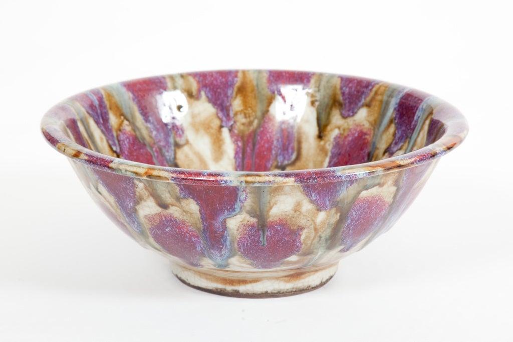 This Chinese Qing Dynasty ceramic bowl with flambé decoration in purple, blue and brownish yellow glazes on a crackled cream glazed ground.