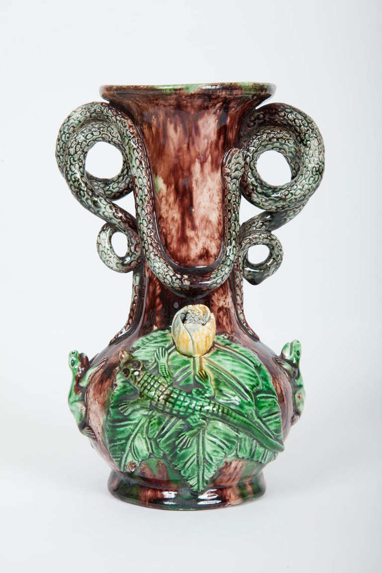 This small mid nineteenth century Portuguese Palissy ware majolica vase is naturalistically decorated with curling snake form handles, lizards, frogs and leaves, all in relief, on a brown mottled ground, with a green mottled ground on the interior.
