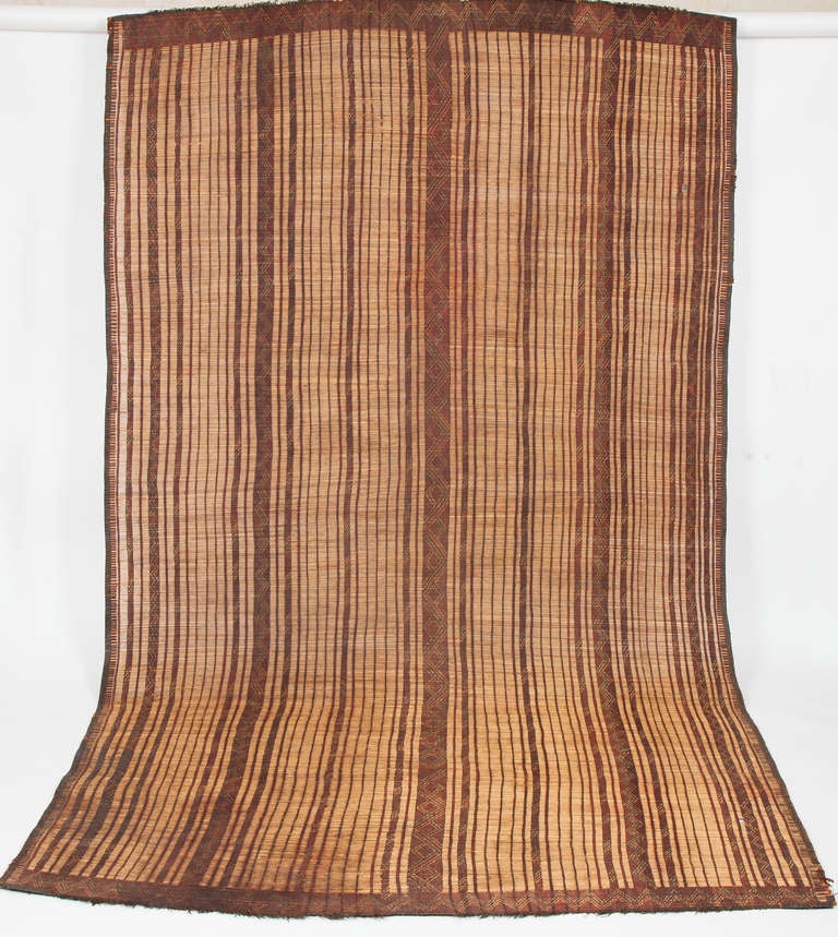Made in the desert of Southern Moroccan and Mauritania by indigenous tribes, Tuareg mats are composed of dwarf palm tree fibers, hand woven with leather stripes, in reddish brown earth tone colors. These mats were traditionally used to cover floors