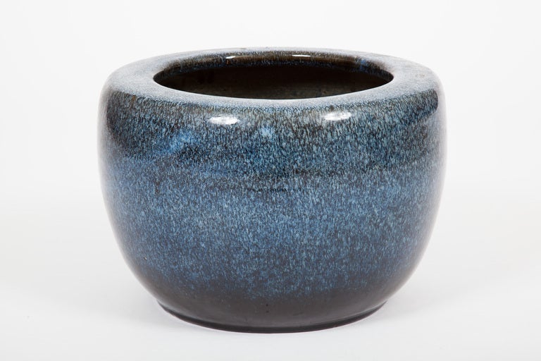 This mid twentieth century Japanese Showa period glazed ceramic hand warmer (hibachi) is circular in form with a compressed low body, soft edged straight shoulder, and wide lip. It is decorated with robin's egg blue mottled glaze, with an unfinished